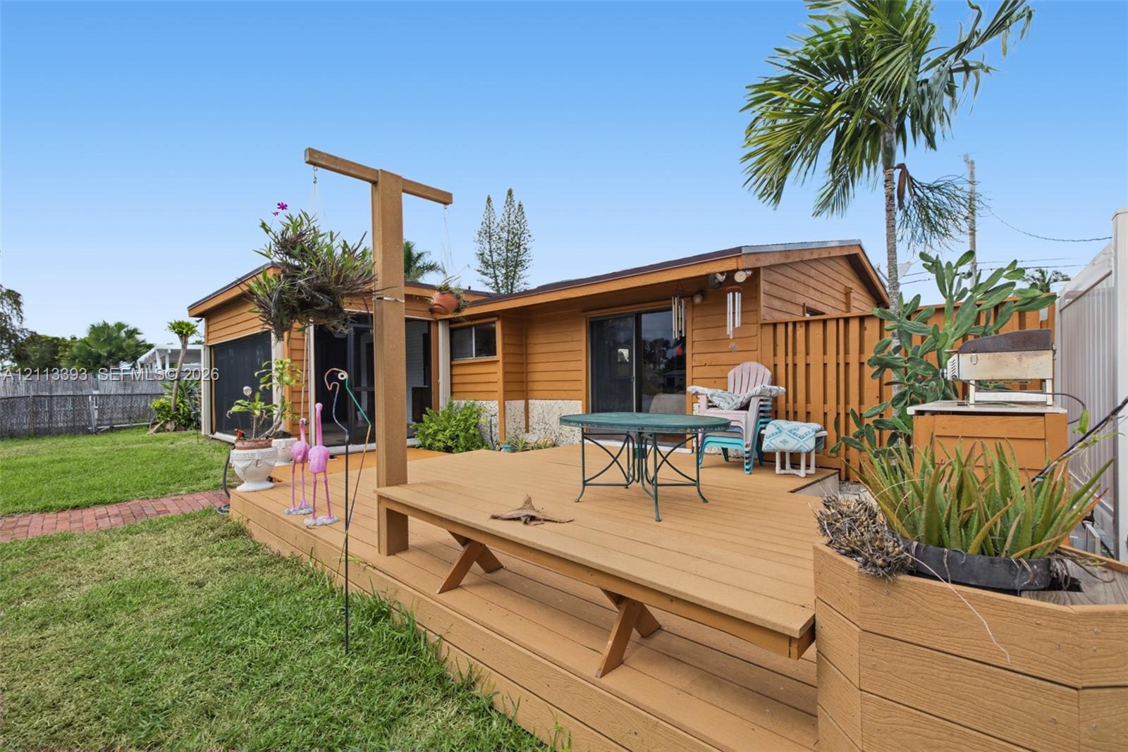 Elevated wood deck with a built-in bench, wood-sided exterior, sliding glass doors, and a wood privacy fence