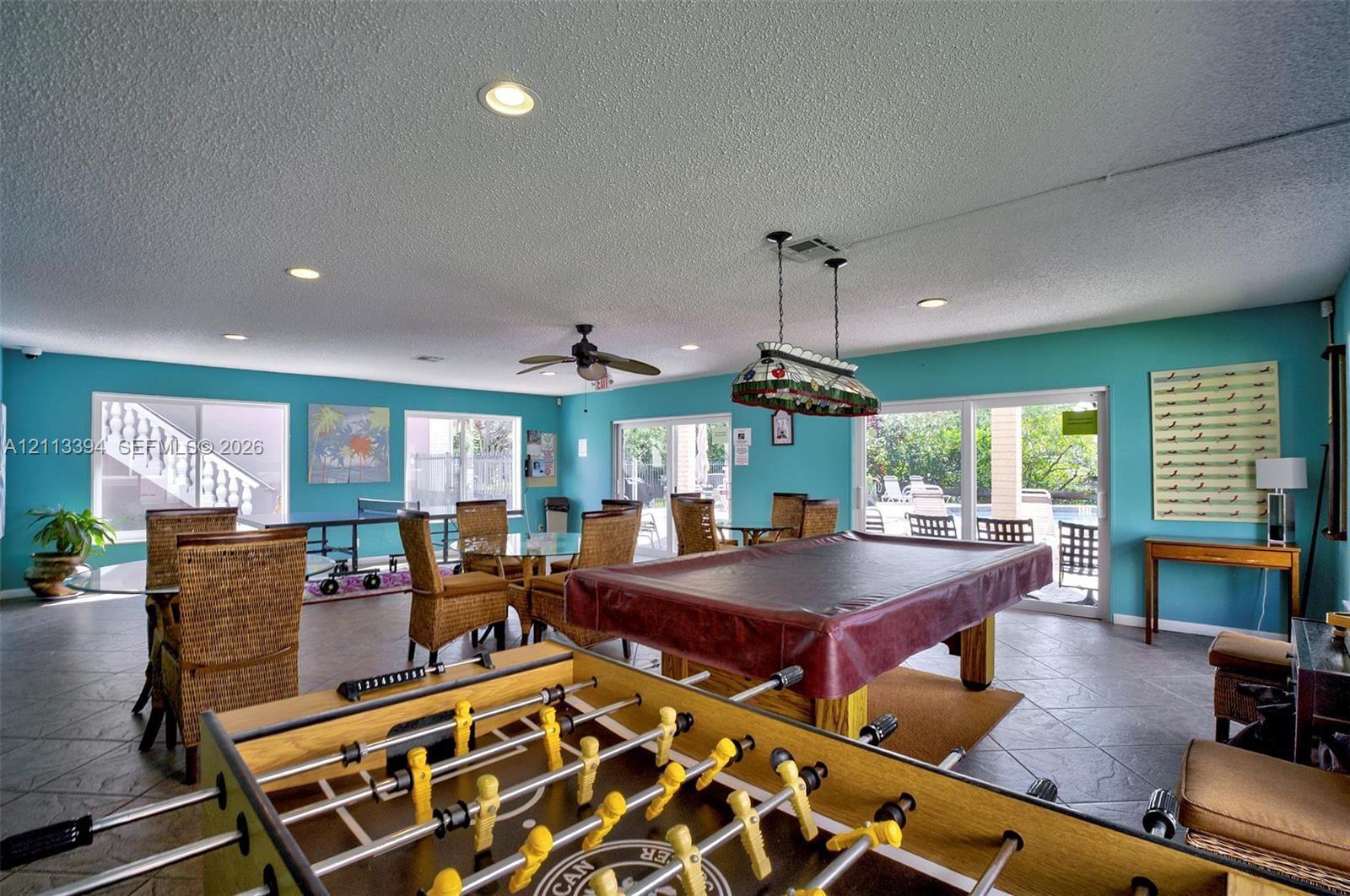 Spacious recreation room featuring neutral tile flooring, recessed lighting, ceiling fan, and sliding glass doors