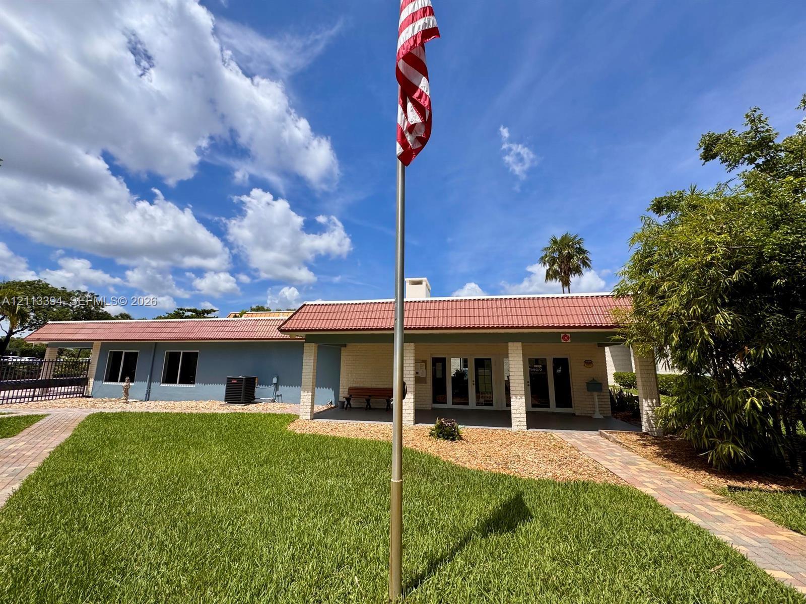 Exterior featuring a red tile roof, covered entryway with brick-style columns, paver walkways, and a manicured lawn
