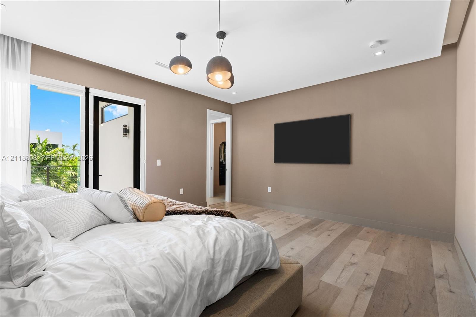 Room featuring wood-finish flooring, dual metal globe pendant lights, and floor-to-ceiling glass door access to an exterior terrace