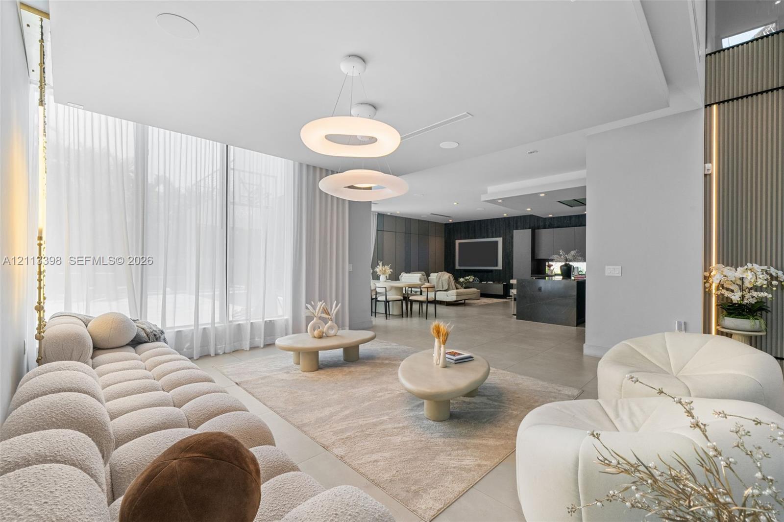 Open-concept interior featuring floor-to-ceiling windows, modern circular pendant lighting, large-format tile flooring, and vertical wall paneling with integrated recessed lighting