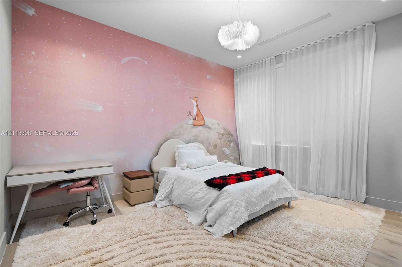 Room featuring large-scale illustrated wall covering, neutral wood-finish flooring, floor-to-ceiling drapery, and a textured pendant light fixture