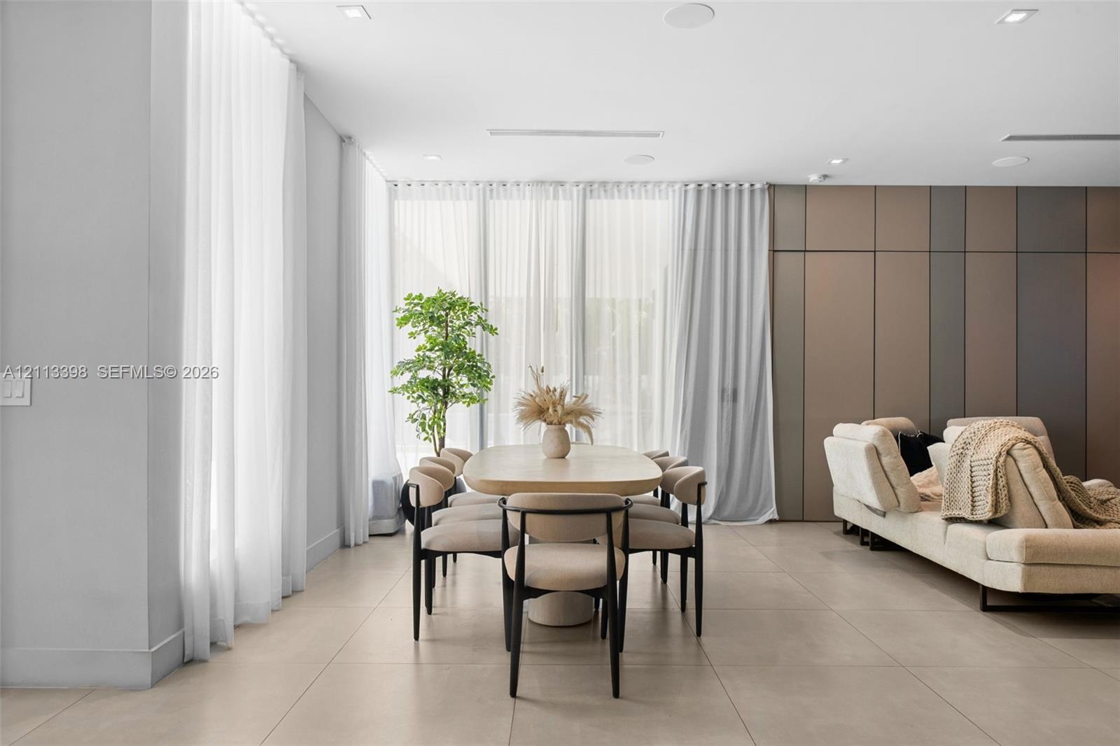 Large-format tile flooring, recessed ceiling lighting, floor-to-ceiling drapery, and multi-tone paneled accent wall