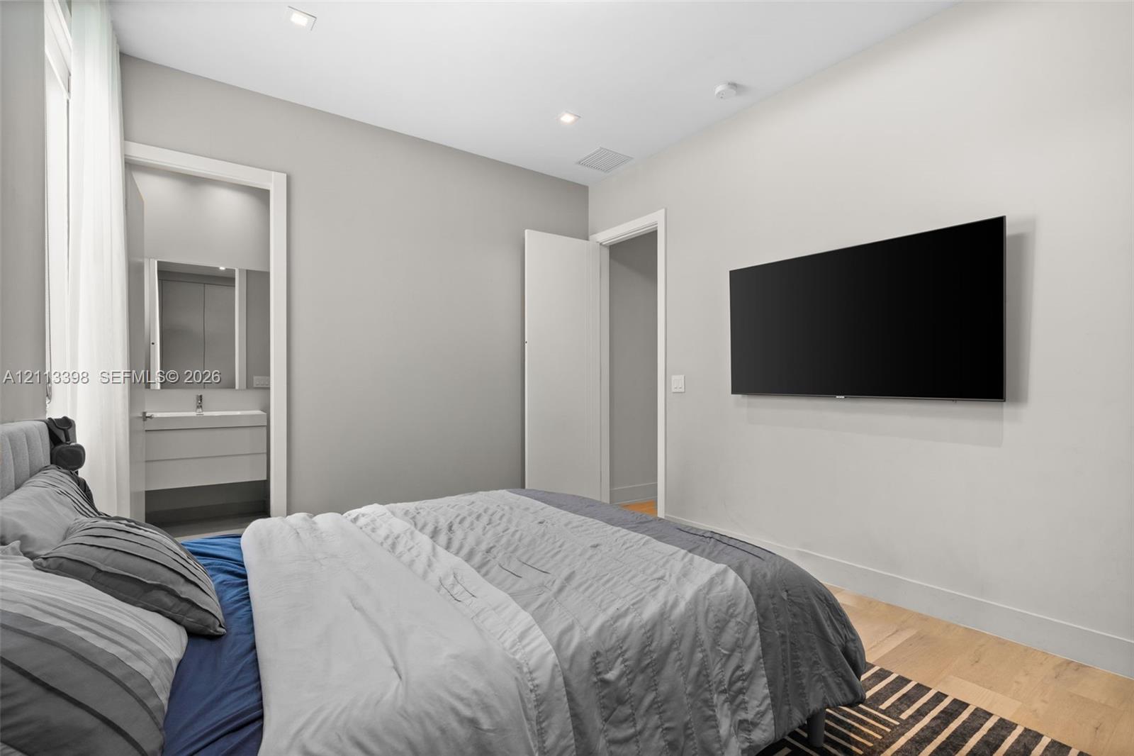 Neutral-toned interior featuring recessed ceiling lighting, light-toned wood-finish flooring, and a wall-mounted display