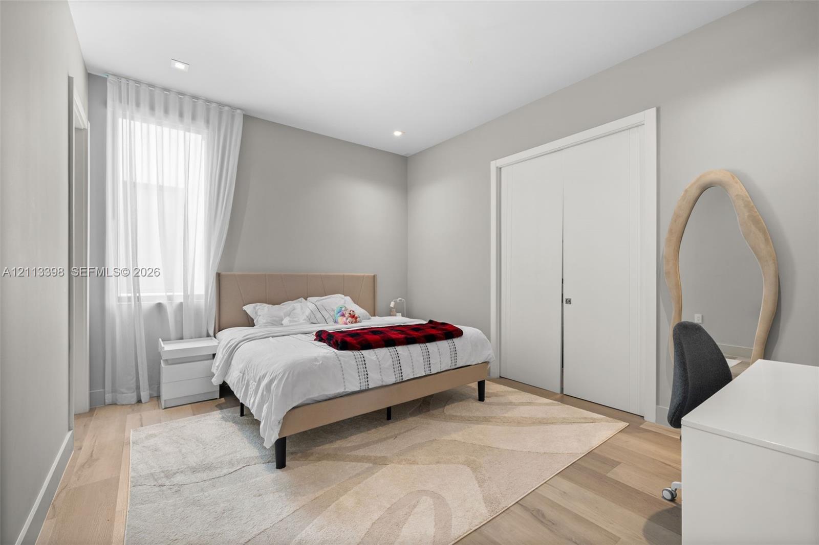 Light-filled room featuring wood-finish flooring, recessed lighting, and a double-door closet with custom-finish trim
