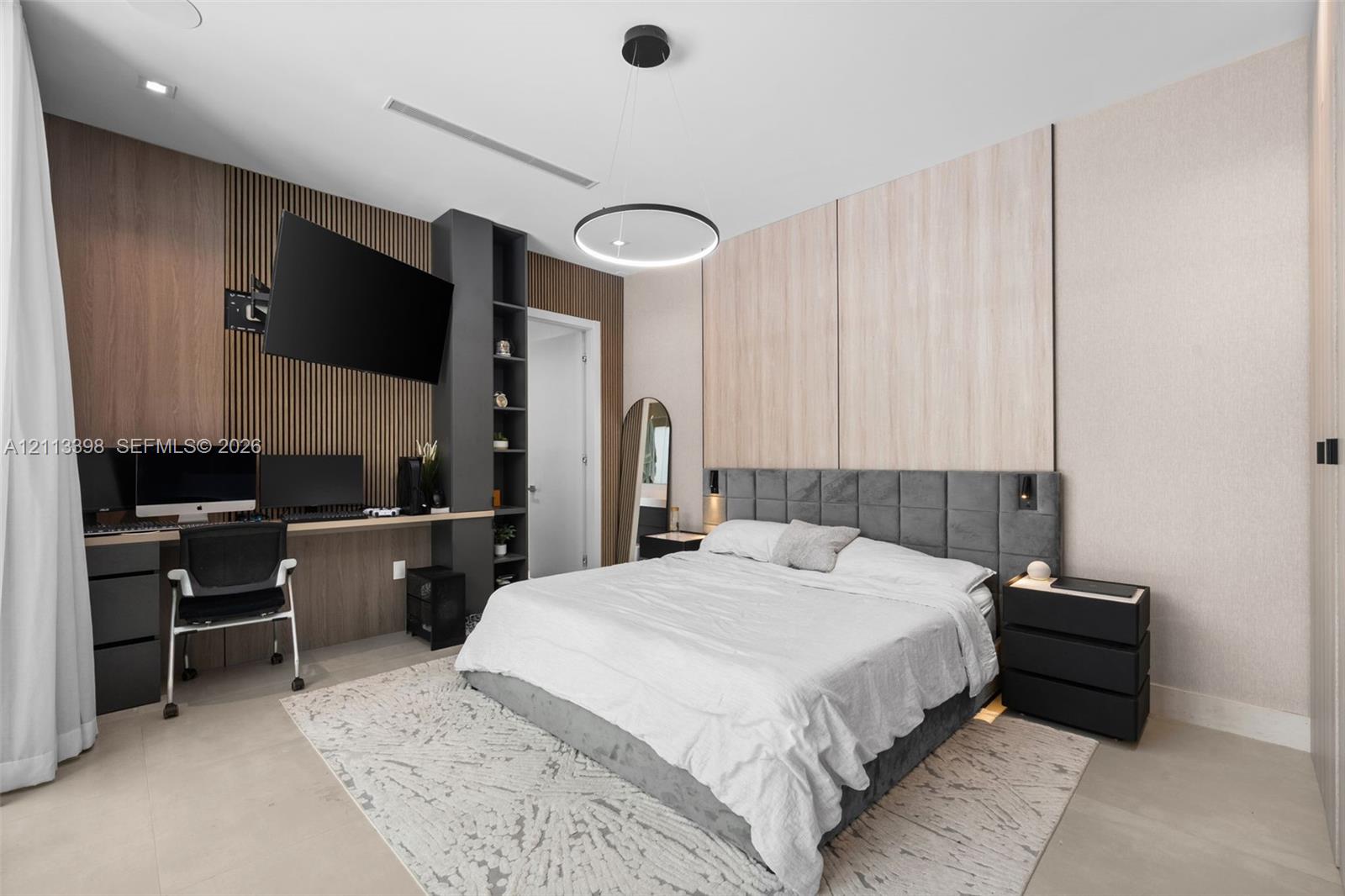 Custom built-in wood-slat desk station with integrated shelving, recessed ceiling lighting, circular pendant light fixture, and dual-tone wall paneling