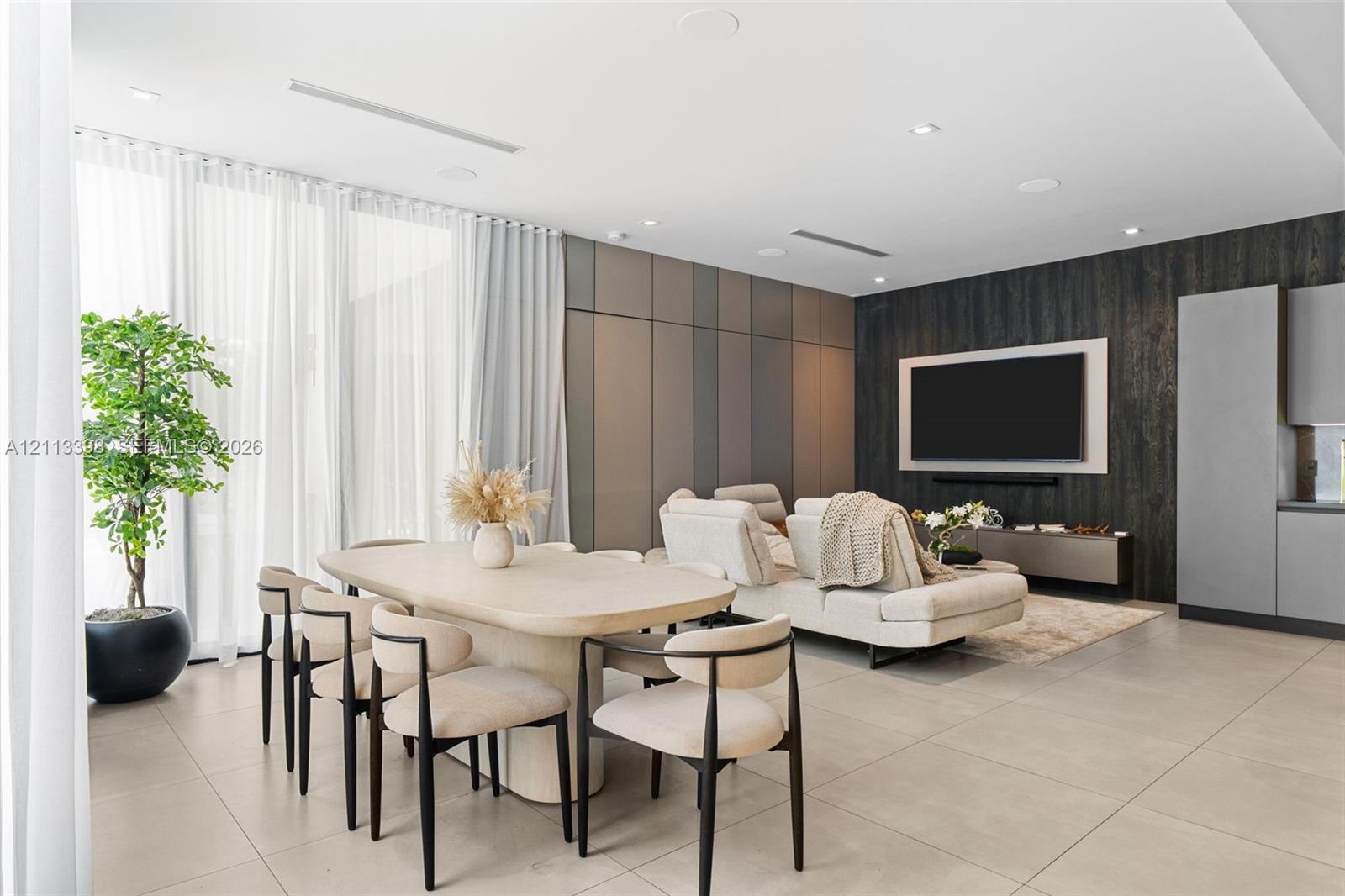 Open-concept living space featuring large-format tile flooring, a custom charcoal textured accent wall, floor-to-ceiling multi-panel feature wall, and recessed ceiling lighting