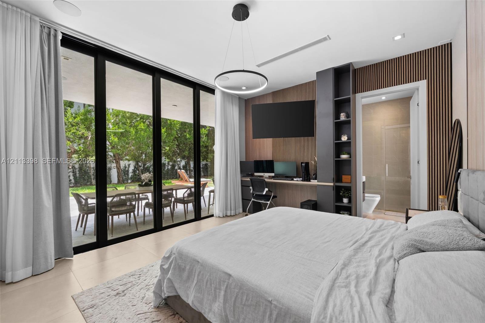 Floor-to-ceiling sliding glass walls, custom wood-slat accent wall, built-in office cabinetry, neutral large-format tile flooring, and minimalist circular pendant lighting