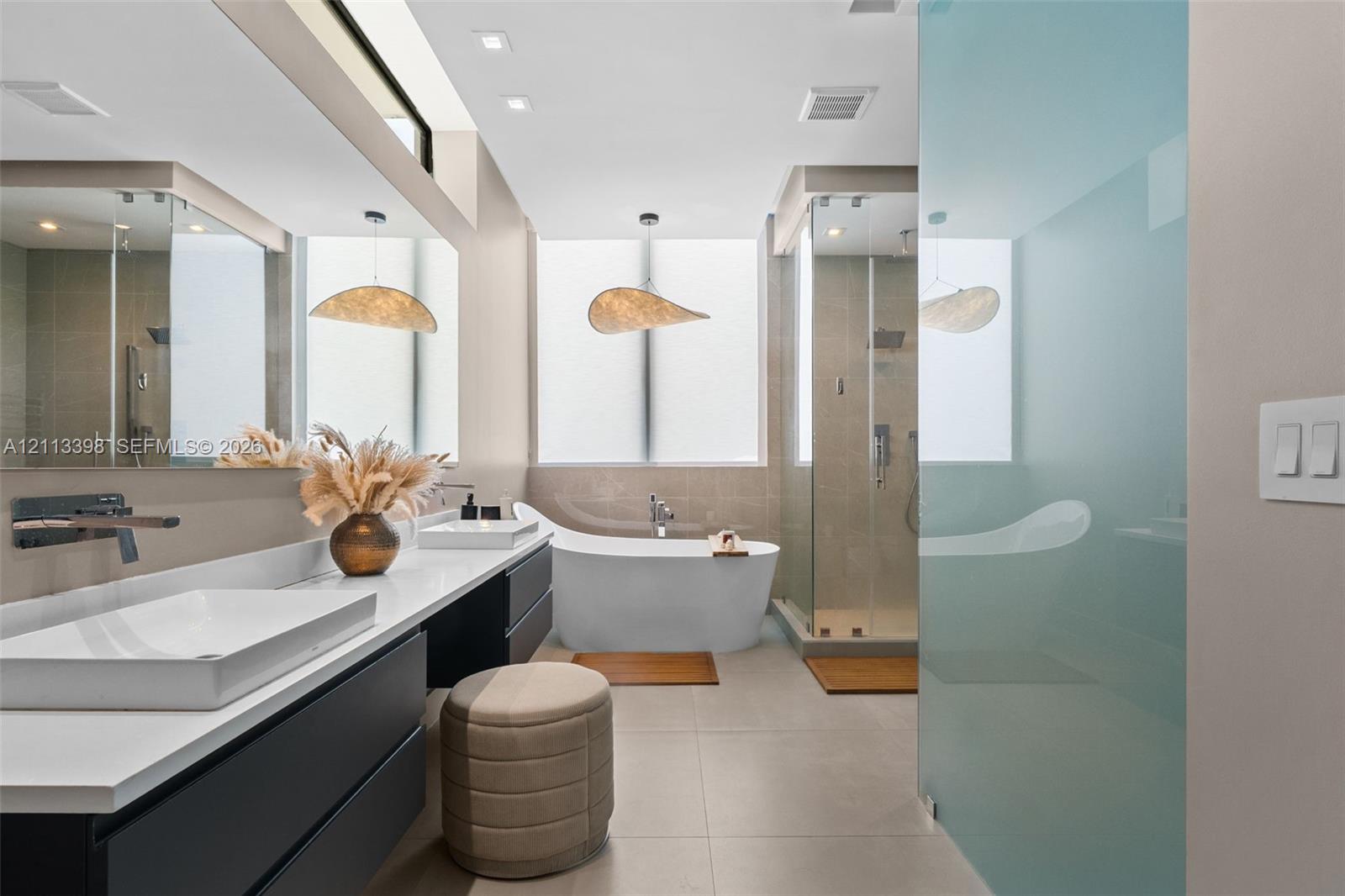 Modern bathroom featuring a floating dual vanity with rectangular vessel sinks, wall-mounted faucets, a freestanding soaking tub, and a glass-enclosed shower with tiled walls