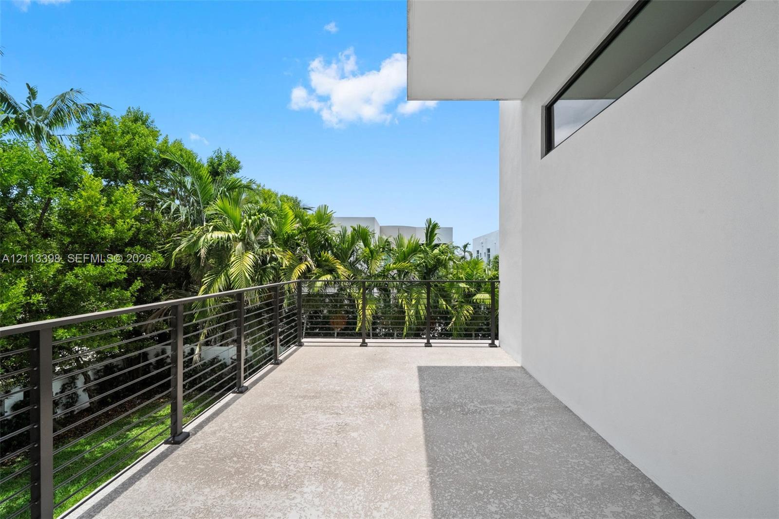 Covered balcony featuring concrete flooring, horizontal cable railing, and stucco exterior finish