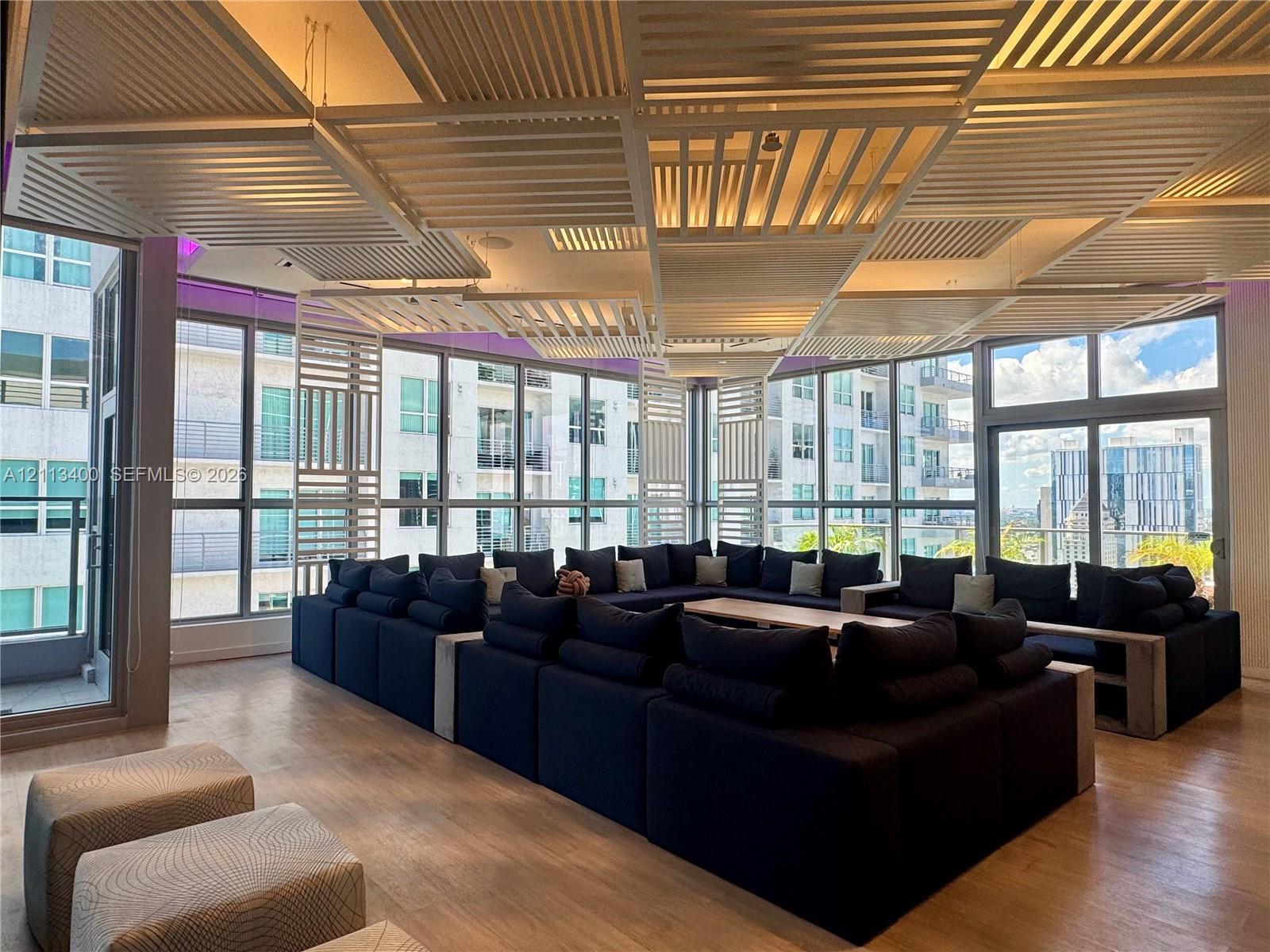 Custom architectural slat ceiling feature, expansive floor-to-ceiling windows, and wood-finish flooring