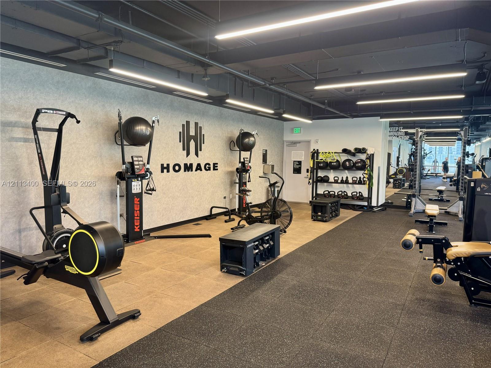 Fitness center featuring industrial-style exposed ceilings, recessed linear LED lighting, and durable two-tone flooring