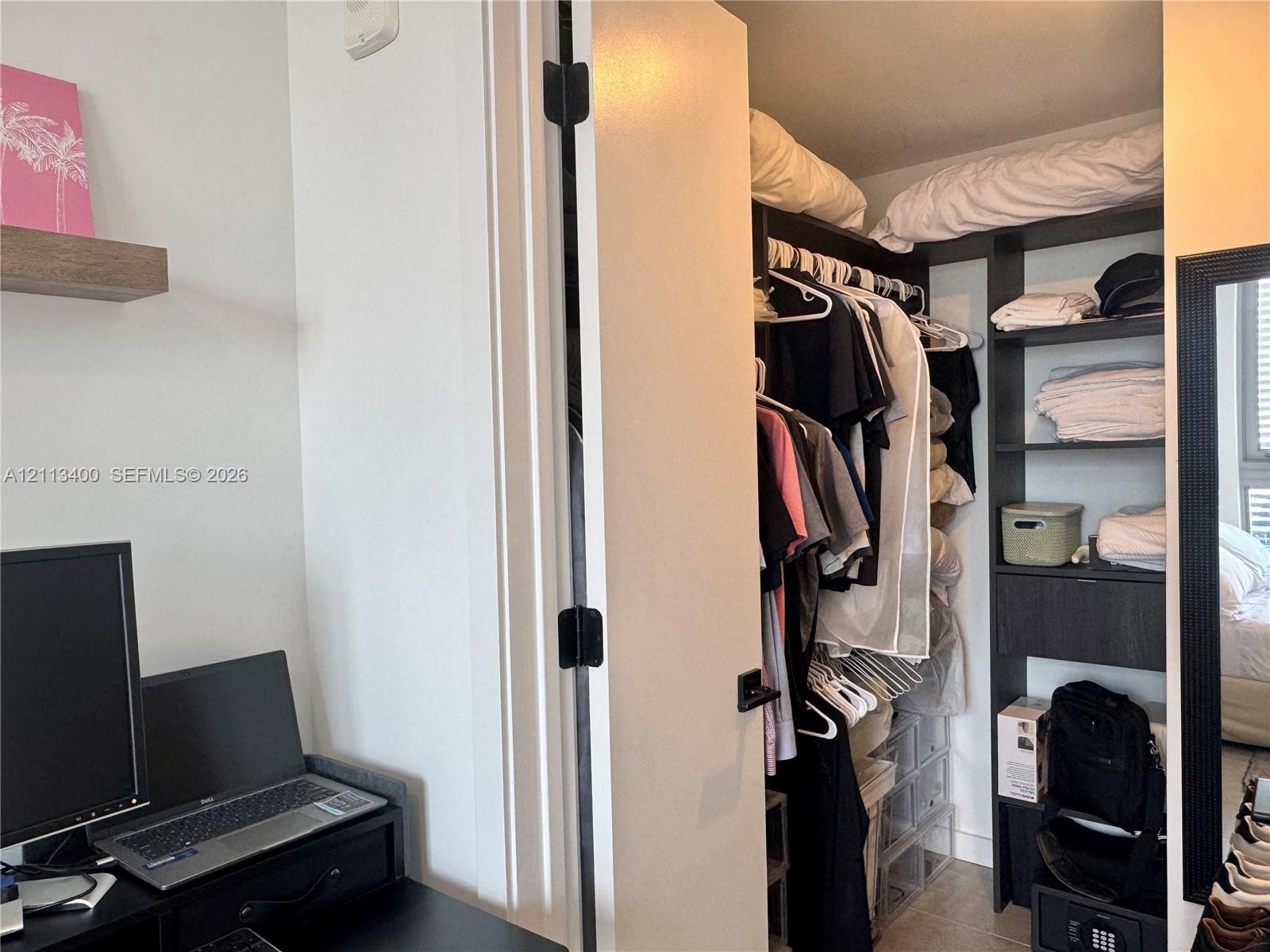 Walk-in closet featuring floor-to-ceiling dark wood-finish shelving, an integrated drawer unit, and a high-hanging rod