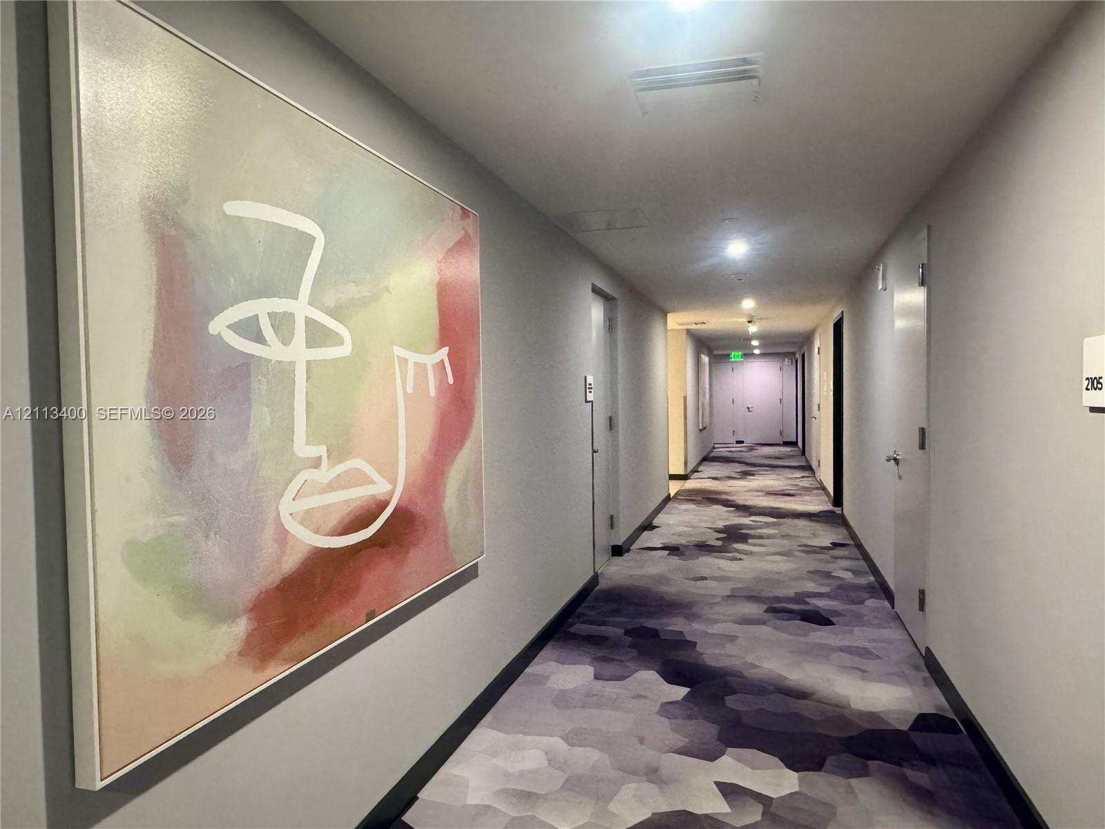 Hallway featuring patterned wall-to-wall carpeting, neutral painted walls, and recessed lighting