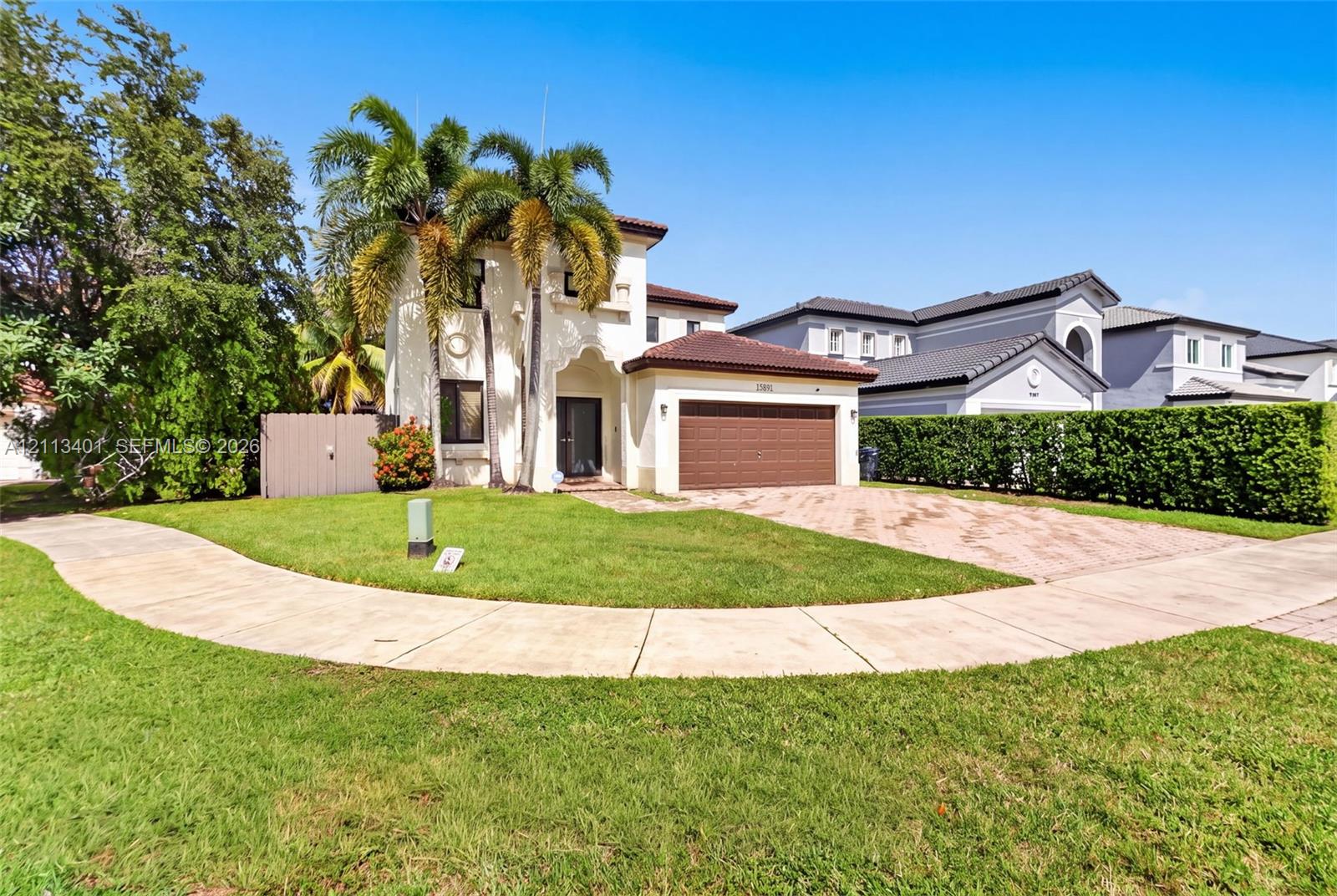 Two-story exterior featuring a tile roof, stucco finish, arched entryway, and a paver driveway leading to an attached garage
