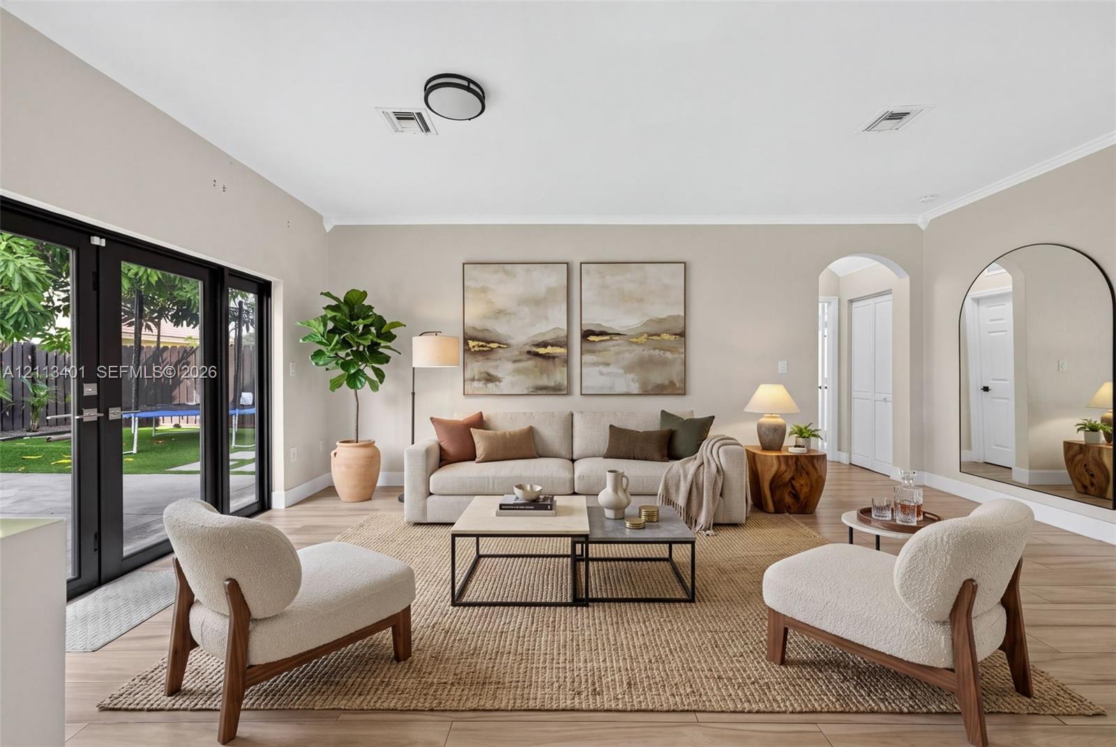 Neutral-toned interior featuring wood-finish flooring, dual black-framed glass panel doors, and an arched entryway