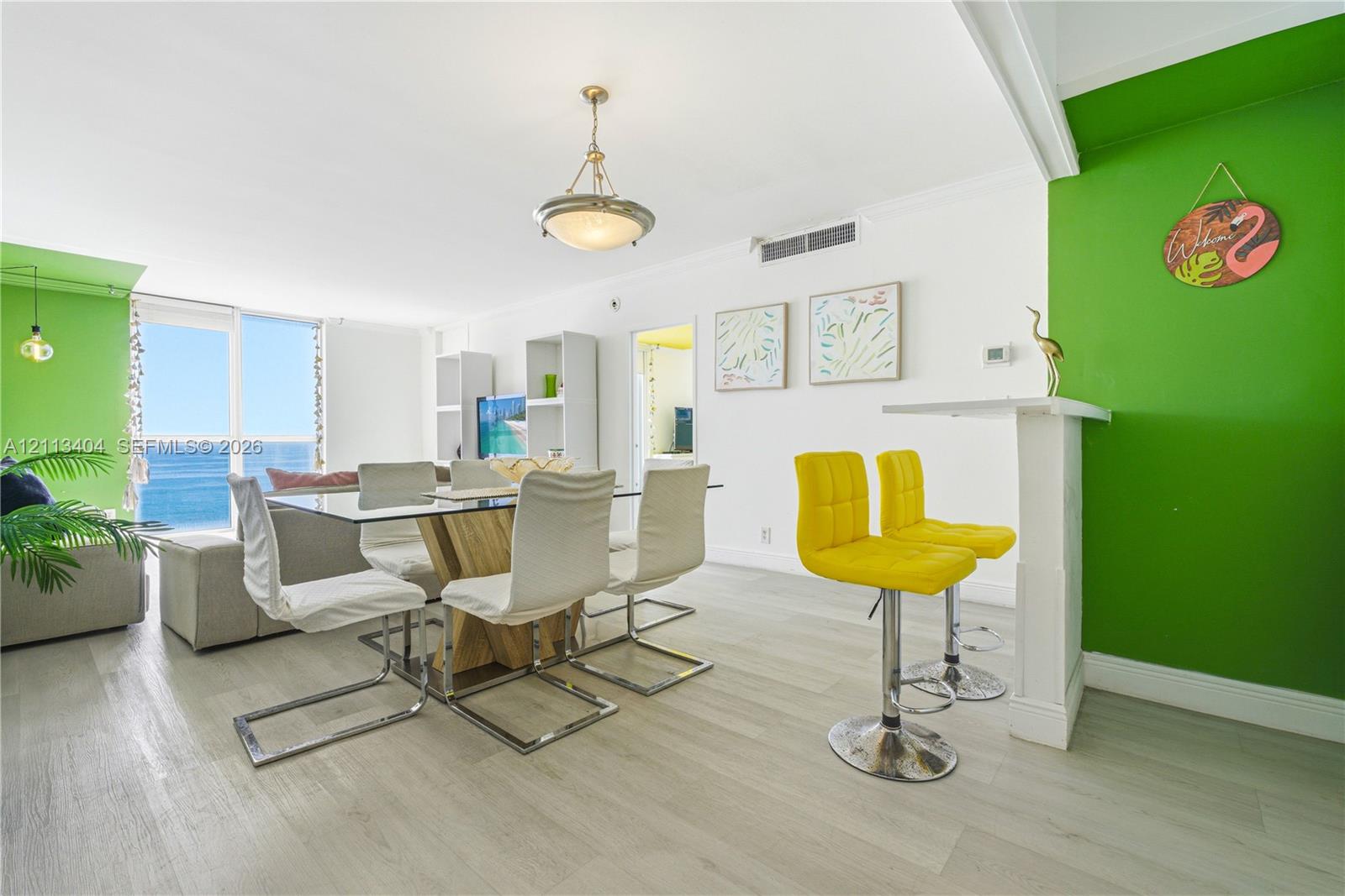Living space featuring wood-finish flooring, floor-to-ceiling glass sliding doors, a built-in breakfast bar, and a hanging pendant light fixture