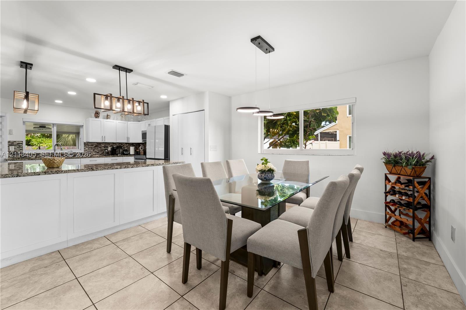 Kitchen featuring white cabinetry, stone-finish countertops, tile flooring, and integrated pendant lighting