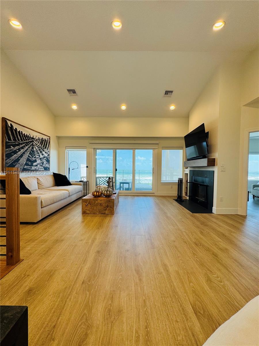 Second floor Vaulted ceilings, wood-finish flooring, recessed lighting, floor-to-ceiling sliding glass doors, and a fireplace with a wood mantel