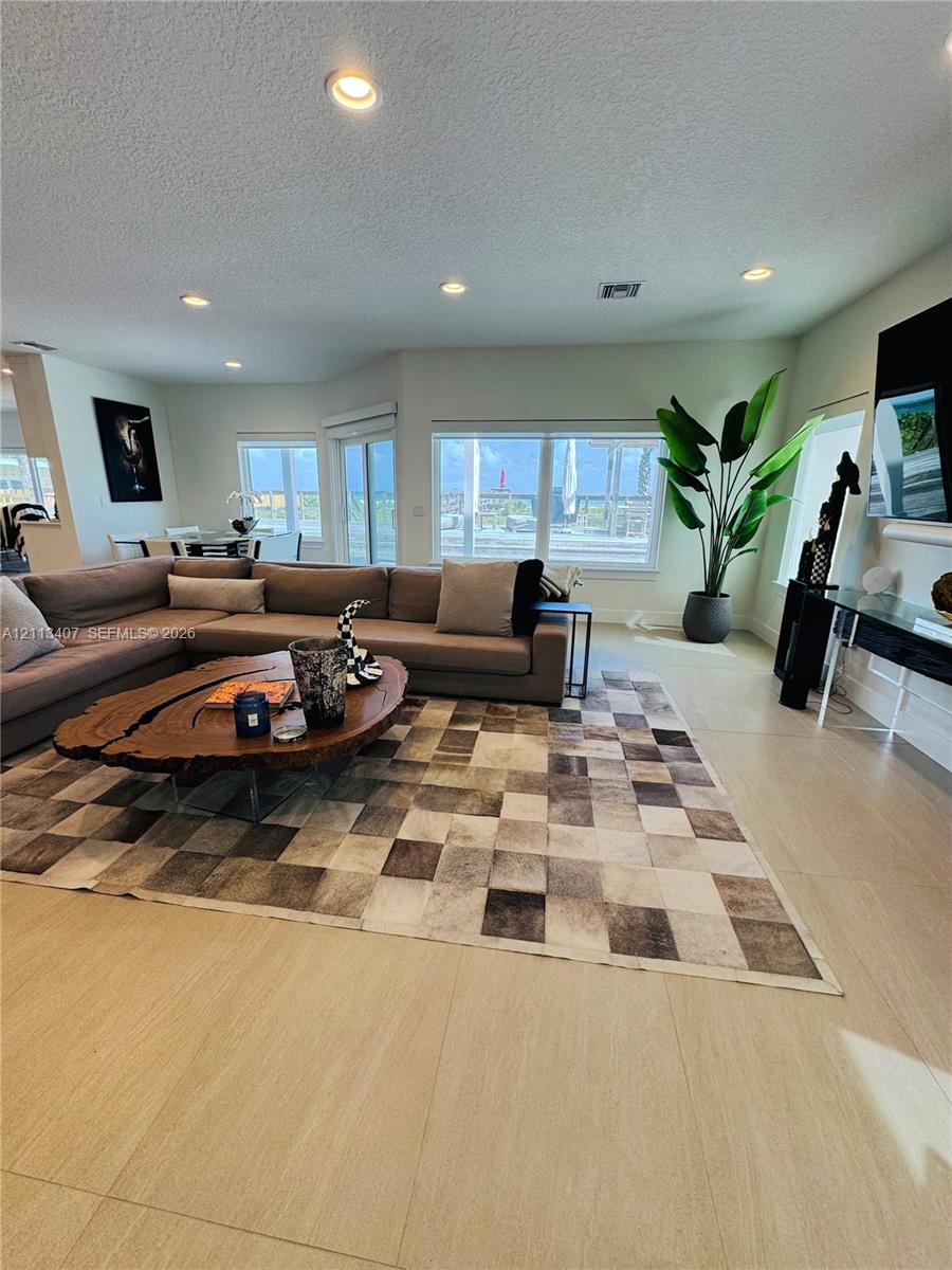 Open-concept interior featuring large-format tile flooring, recessed ceiling lighting, and multiple windows providing natural illumination Open-concept interior featuring large-format tile flooring, recessed ceiling lighting, and multiple windows providing natural illumination