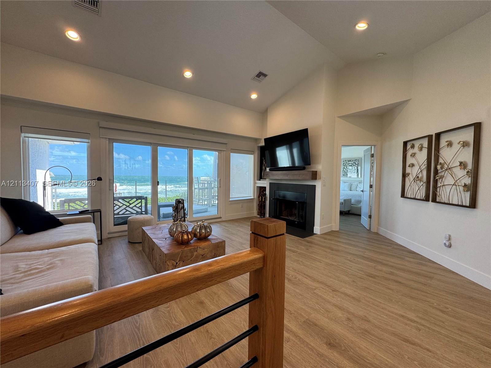 Second floor Vaulted ceilings, wood-finish flooring, floor-to-ceiling sliding glass doors, and fireplace with a wood mantel