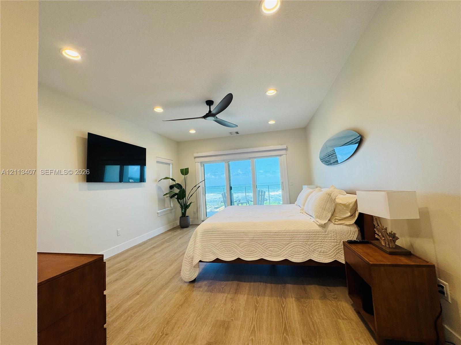 Second floor Wood-finish flooring, recessed lighting, ceiling fan, and sliding glass doors with an ocean backdrop