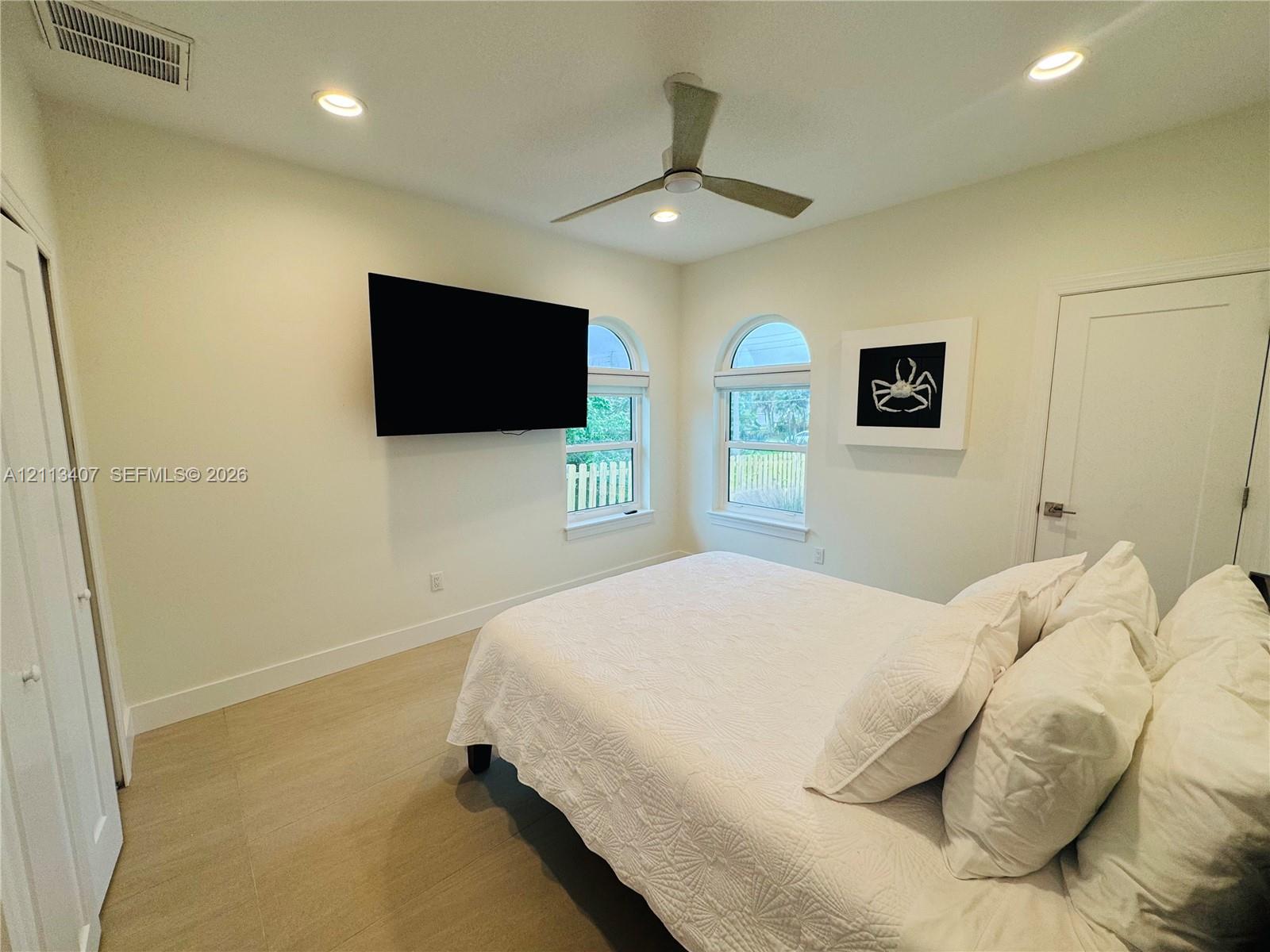 Room featuring neutral walls, wood-finish flooring, recessed lighting, a modern ceiling fan, and arched windows