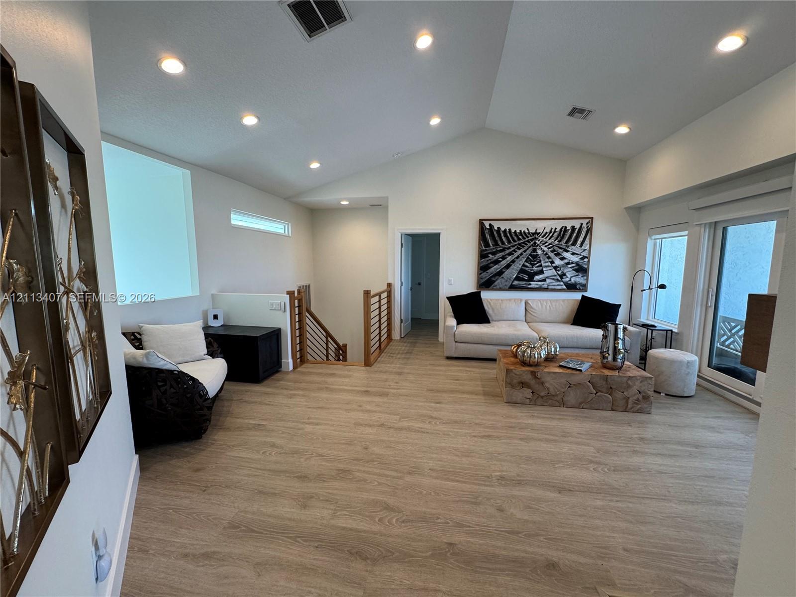 Second floor Vaulted ceilings, wood-finish flooring, recessed lighting, and a stairwell featuring horizontal wood railings