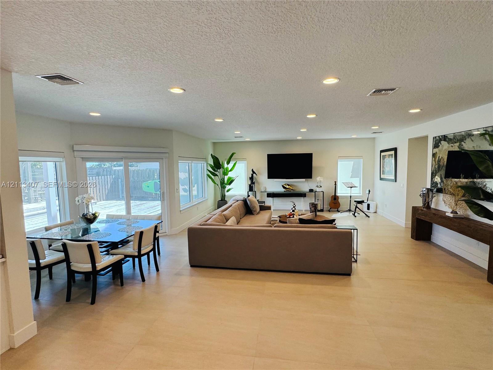 Open concept living area featuring large-format tile flooring, recessed lighting, and sliding glass doors Open concept living area featuring large-format tile flooring, recessed lighting, and sliding glass doors