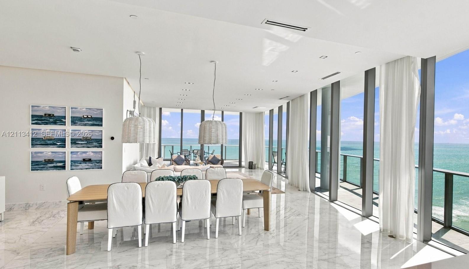 Open-concept living space featuring floor-to-ceiling windows, polished stone flooring, recessed lighting, and dual woven pendant light fixtures