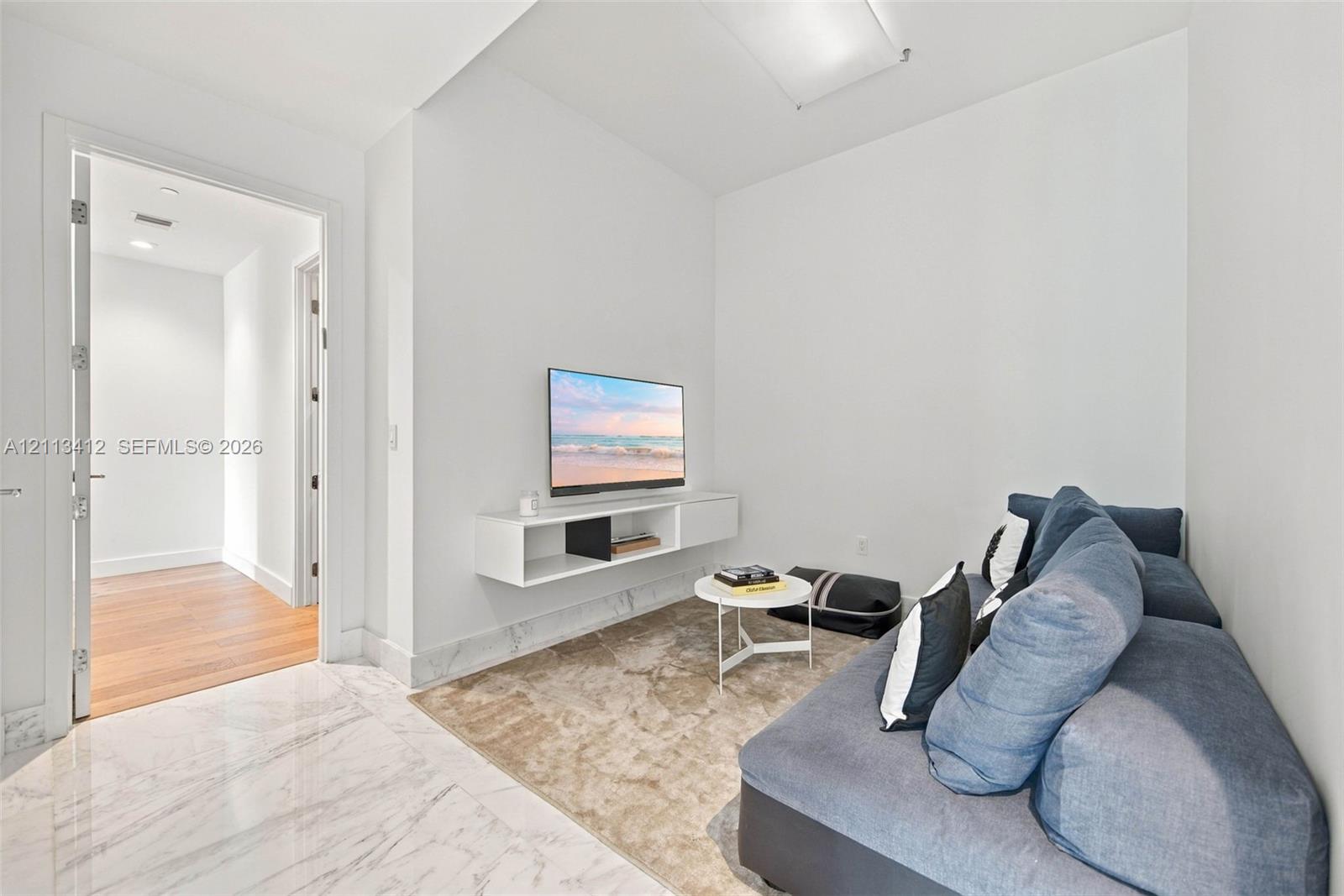 Polished stone flooring, wood-finish flooring, and wall-mounted white cabinetry