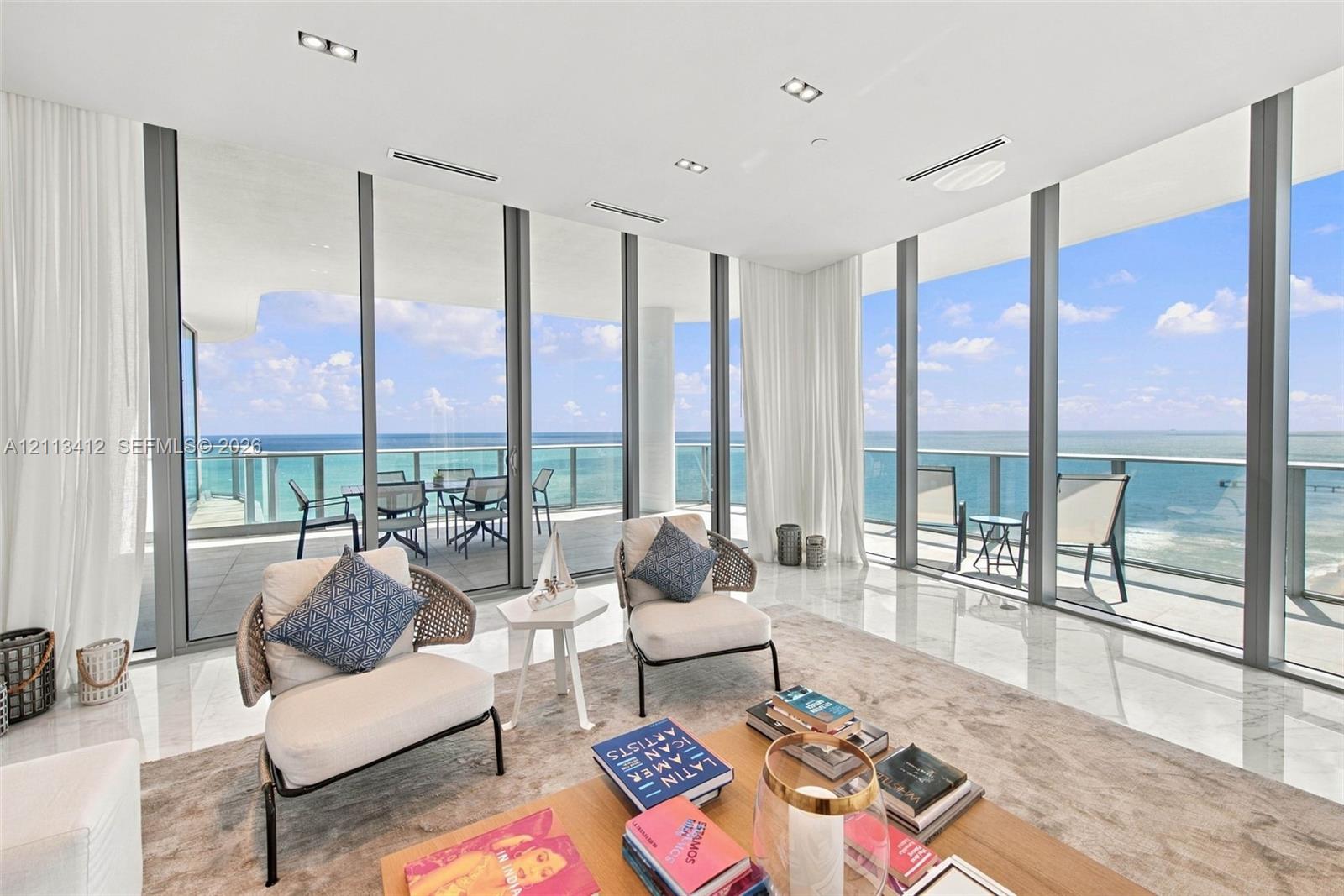 Floor-to-ceiling glass walls, expansive balcony, stone-finish flooring, recessed ceiling lighting, and horizontal ocean backdrop Floor-to-ceiling glass walls, expansive balcony, stone-finish flooring, recessed ceiling lighting, and horizontal ocean backdrop