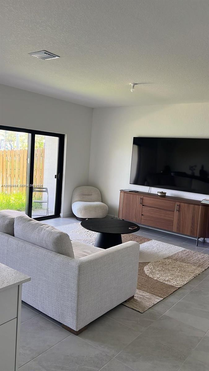 Interior space featuring large-format tile flooring, neutral wall finishes, and black-framed sliding glass doors