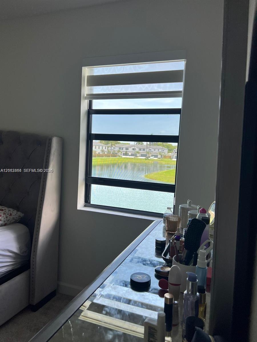 Single-pane window with a black frame, featuring retractable dual-layer blinds and water-fronting exterior exposure