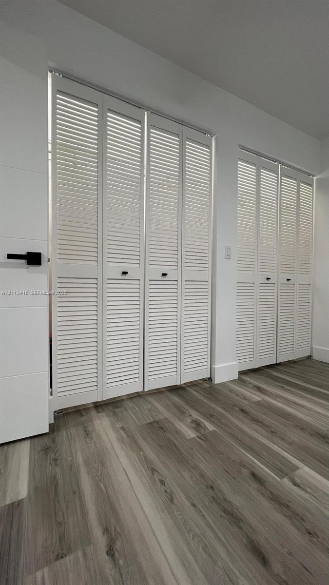 Wood-finish flooring paired with white louvered bifold doors featuring matte black hardware