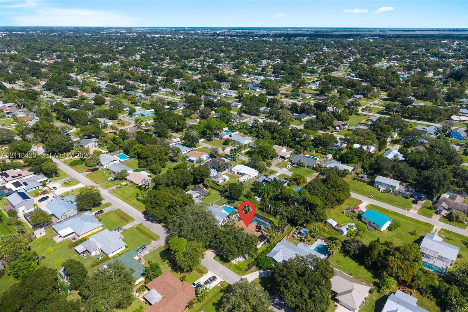 Aerial perspective featuring a residential lot with a backyard swimming pool, mature canopy trees, and established landscaping