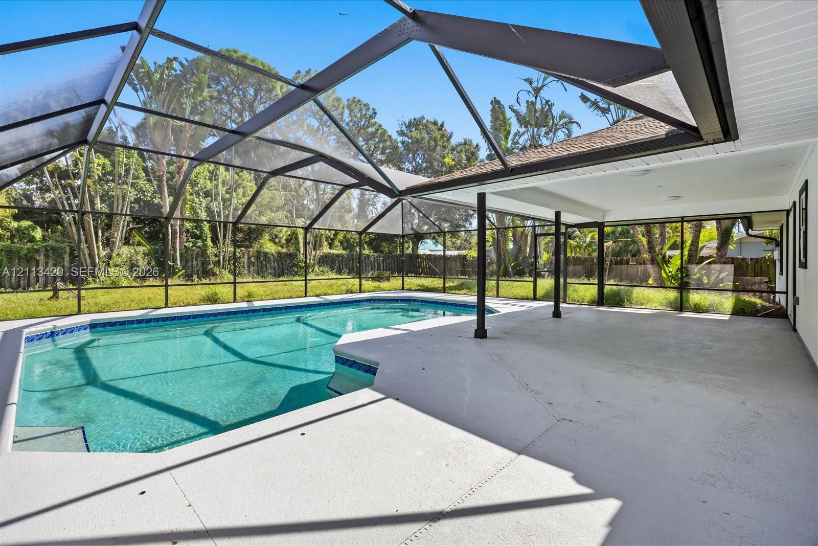 Screened lanai featuring a concrete deck, covered patio space, and a swimming pool