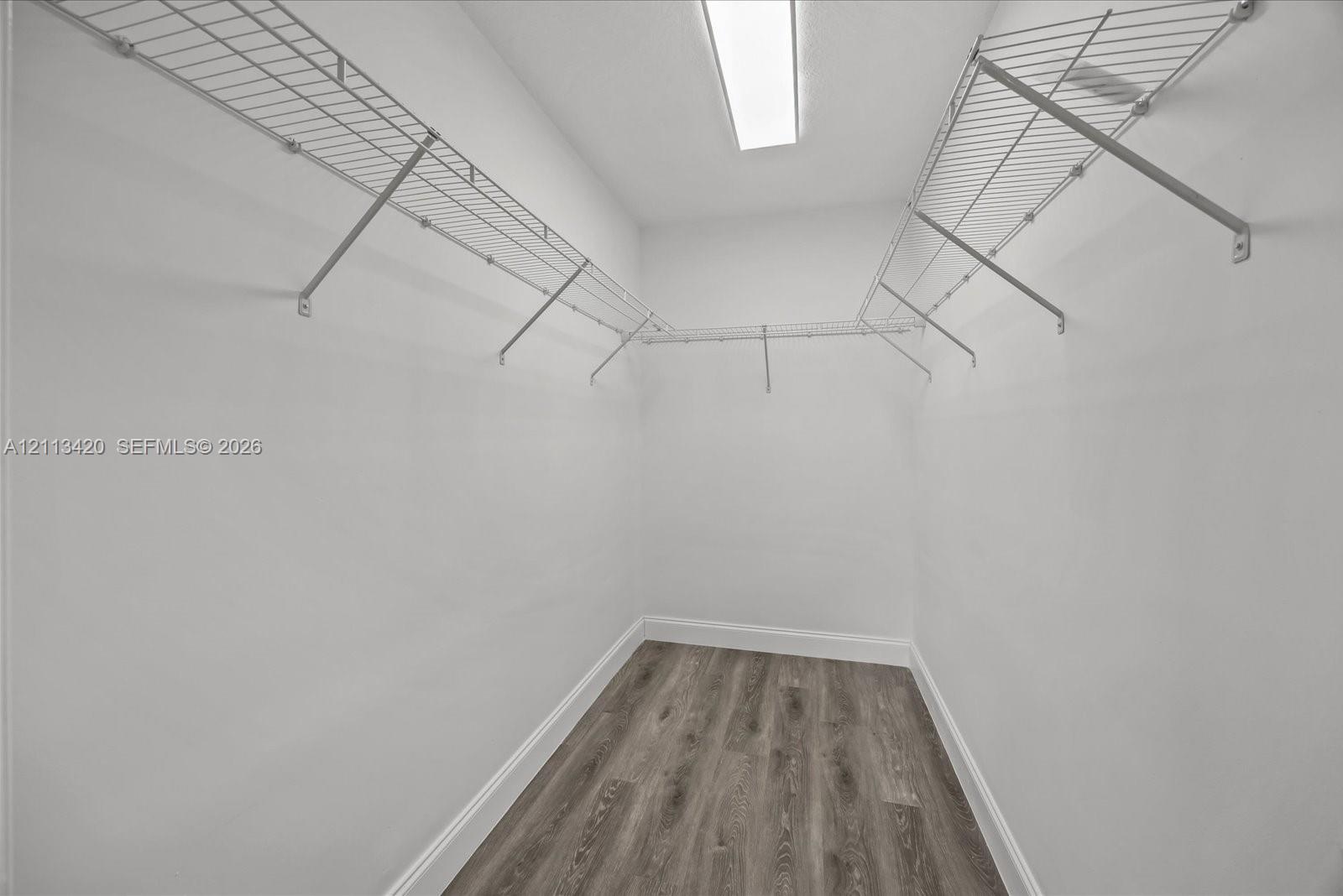 Walk-in closet featuring white walls, wood-finish flooring, and integrated white wire shelving