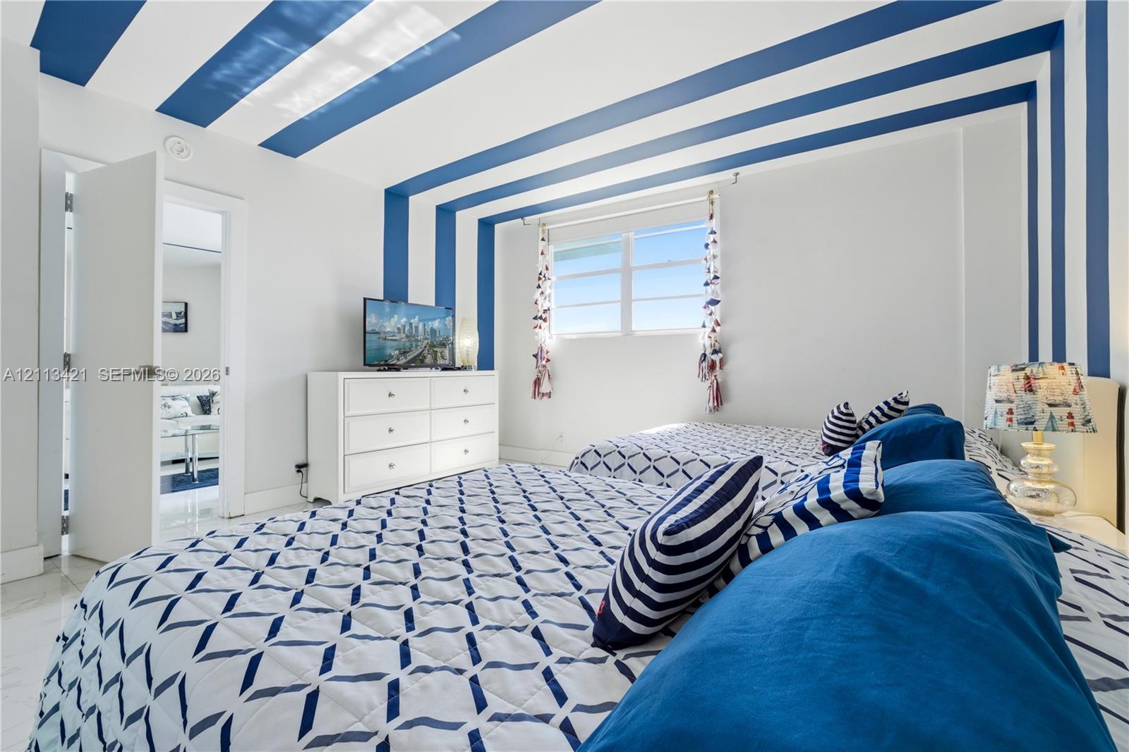 Room interior featuring smooth-finish light-toned flooring, expansive horizontal sliding windows, and a decorative ceiling treatment with painted structural accents