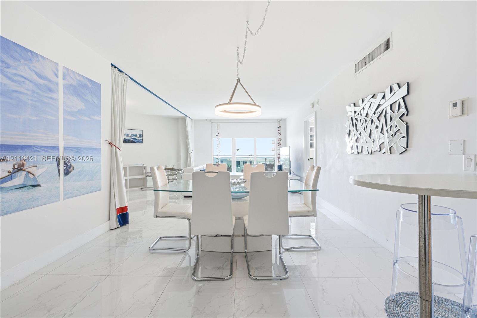 Open-concept space featuring polished stone-finish tile flooring, a contemporary circular pendant light, and recessed ceiling lighting