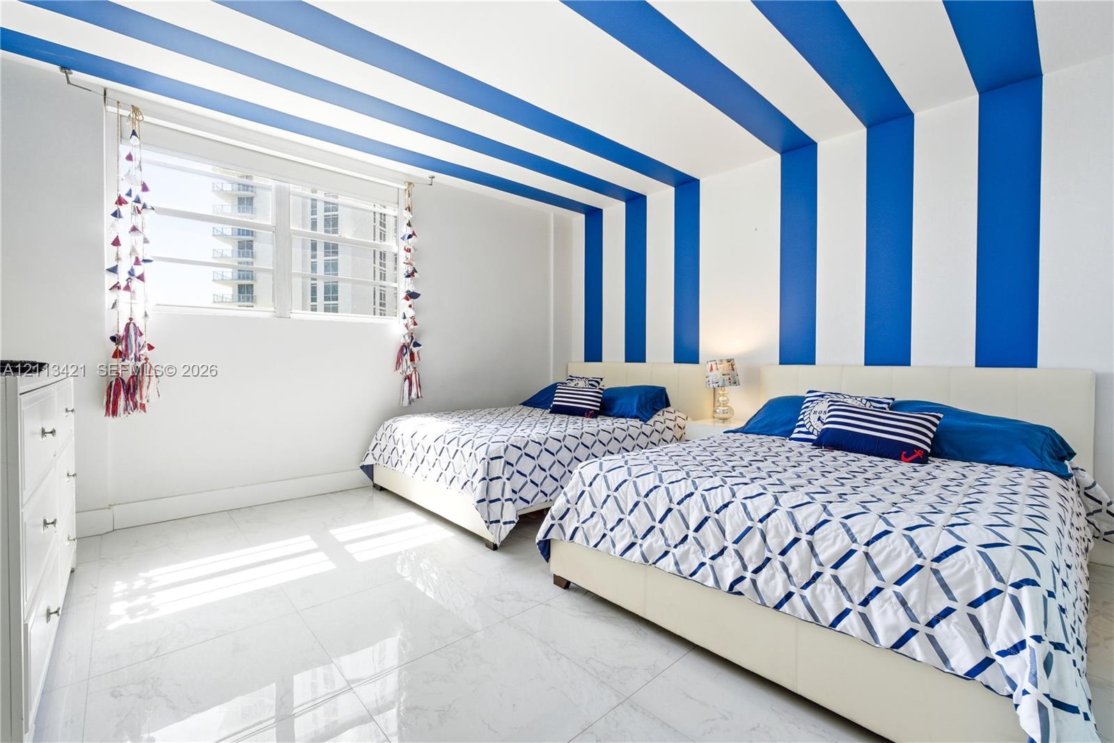 Room featuring large-format polished tile flooring, expansive multi-pane window, and distinctive wall-to-ceiling blue and white vertical accent stripes