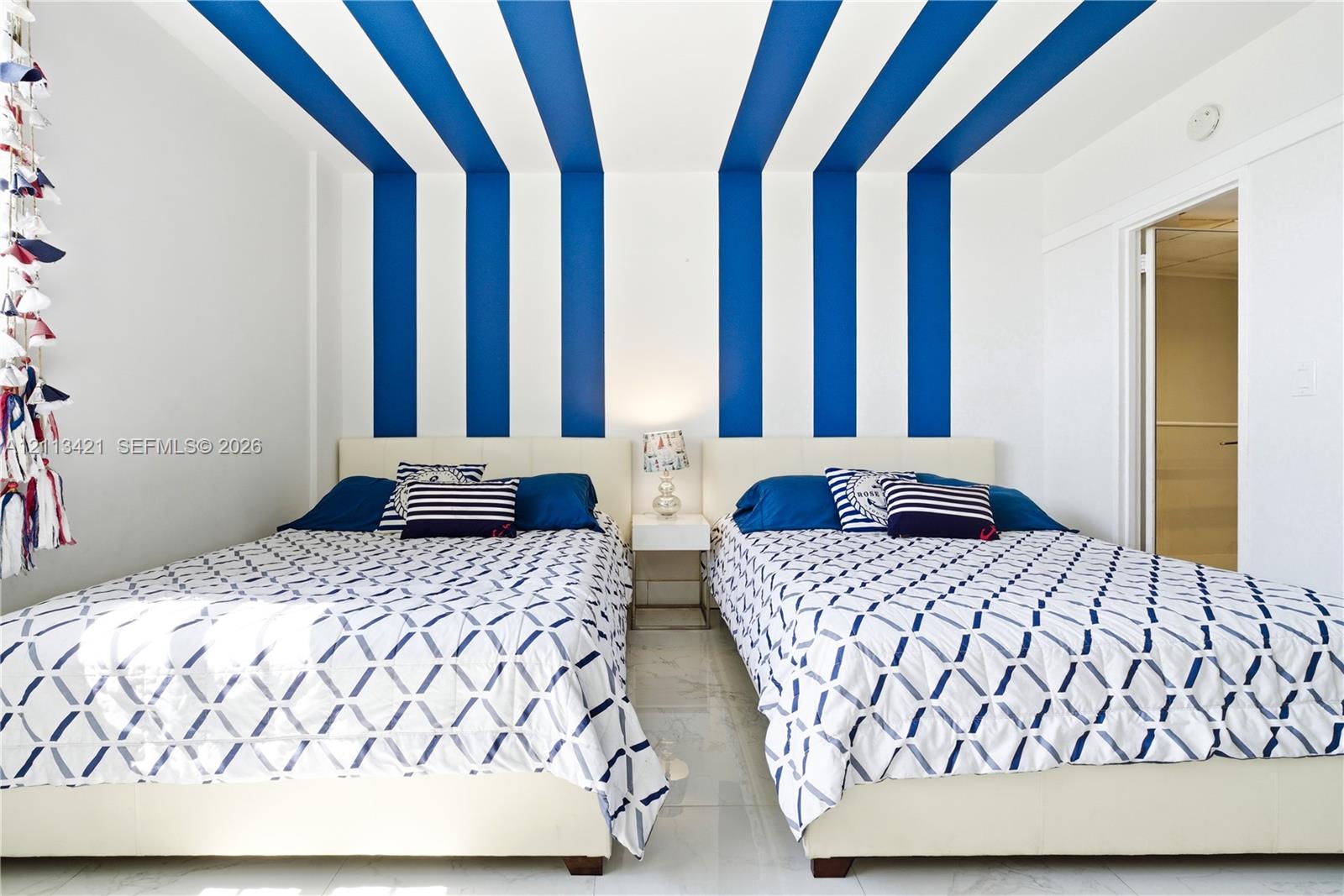 Room featuring high-contrast blue and white vertical wall and ceiling stripes, polished tile flooring, and a recessed doorway