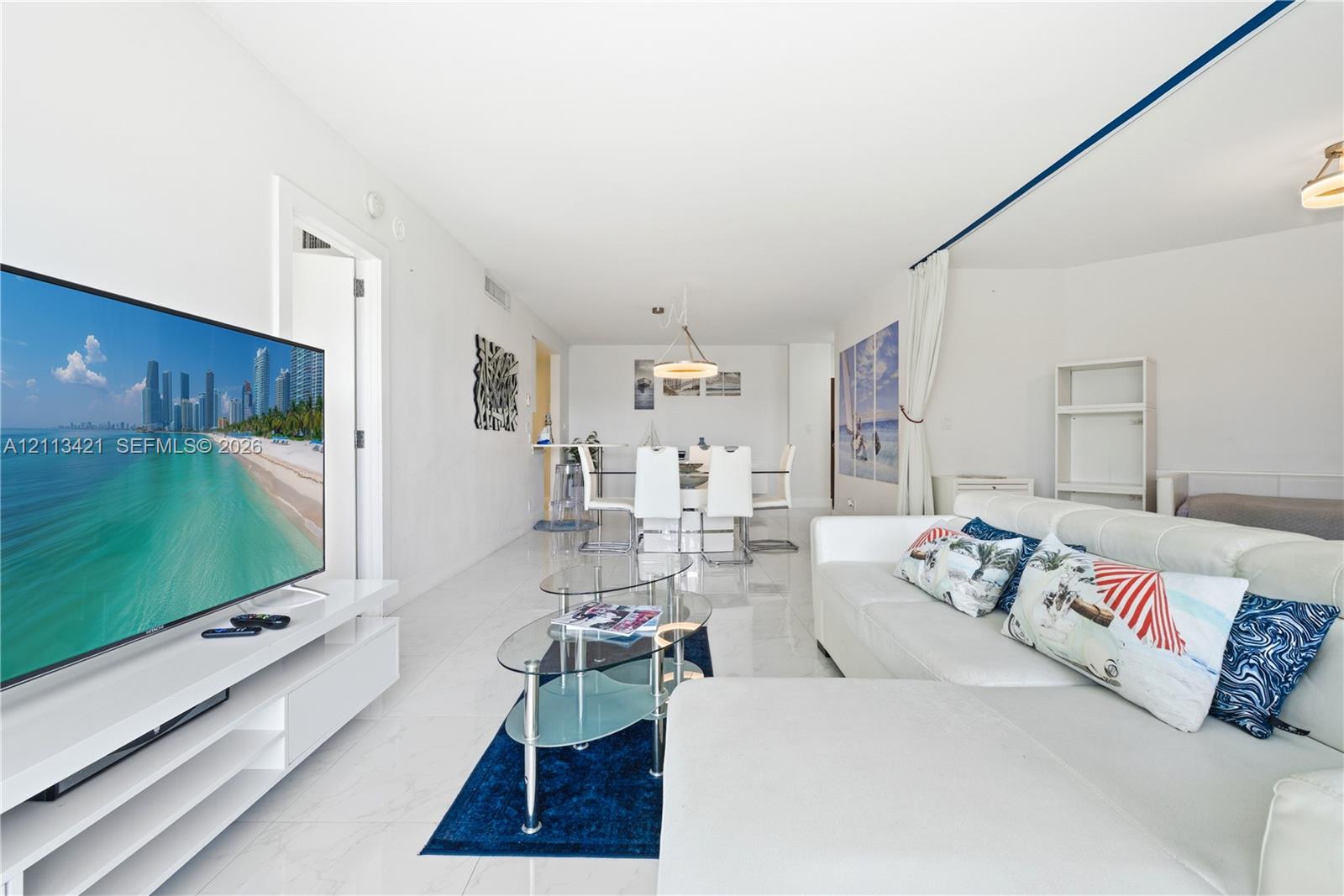 Open-concept interior featuring large-format tile flooring, recessed lighting, and a white built-in media console