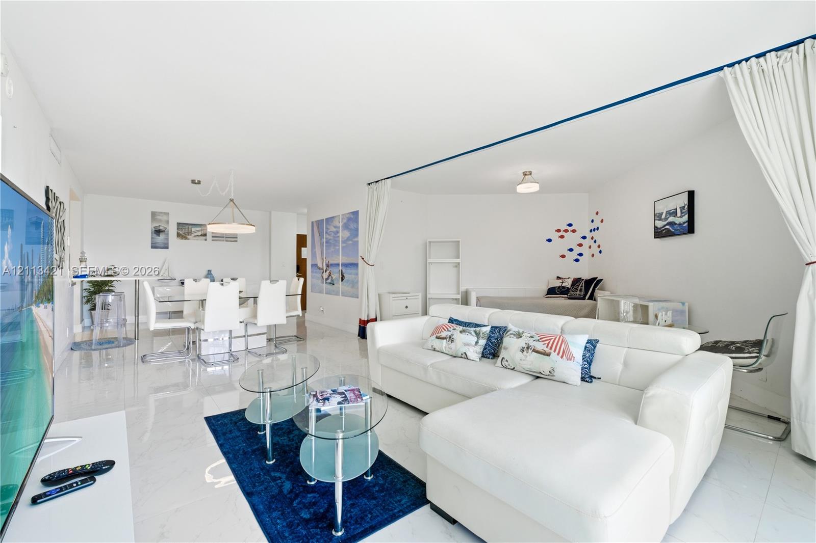 Open-concept interior featuring large-format tile flooring, recessed ceiling lighting, and a geometric pendant light fixture