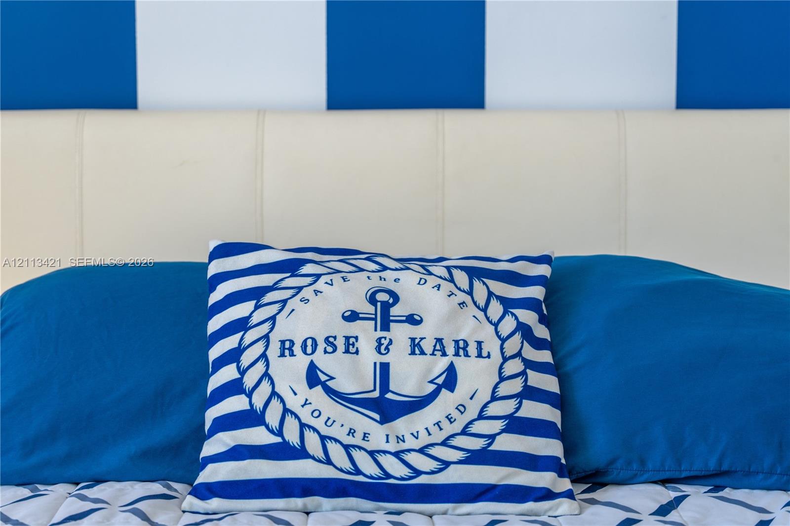 Blue and white vertically striped wall treatment and off-white upholstered headboard