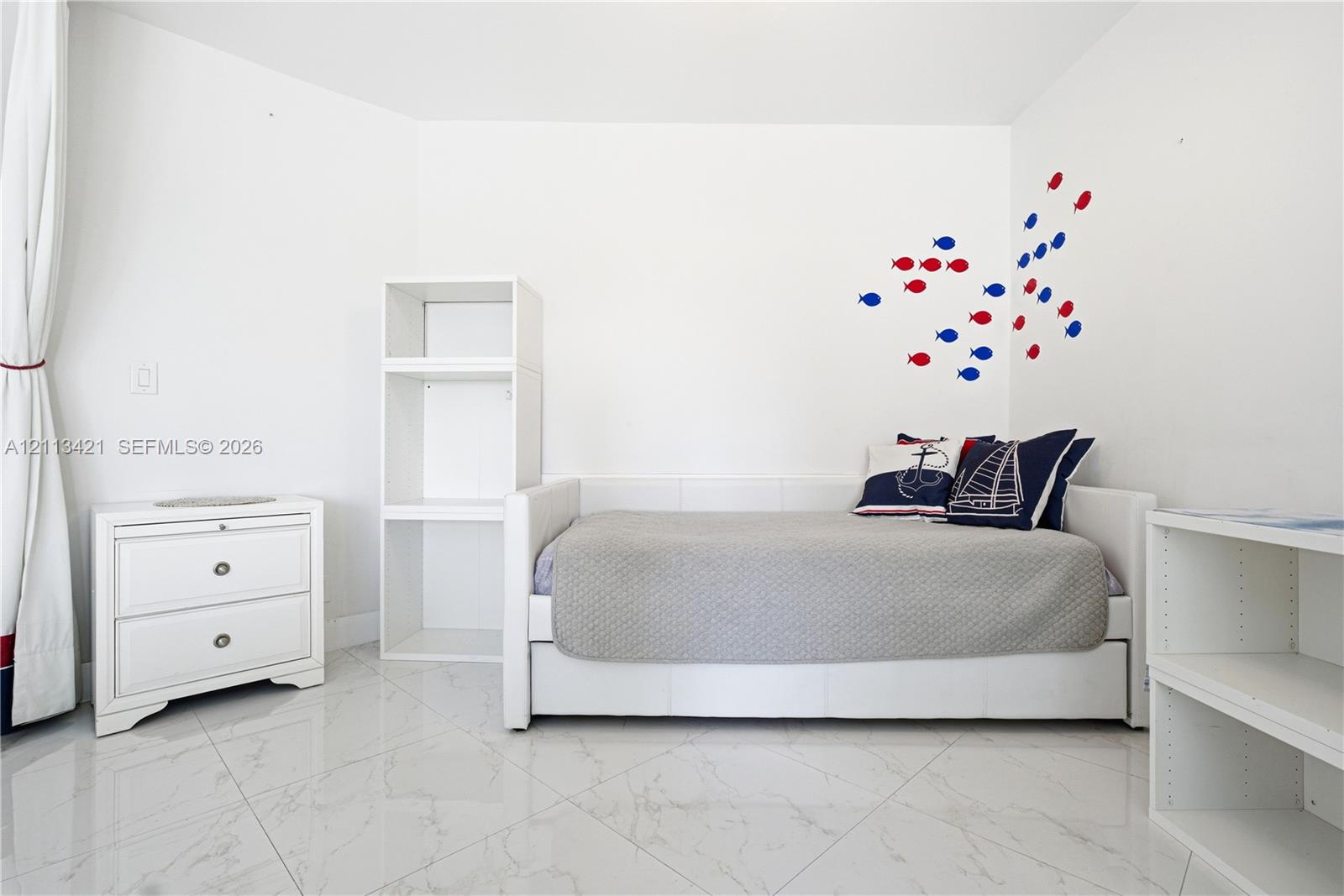 Bright interior space featuring polished tile flooring, white built-in shelving units, and clean white walls