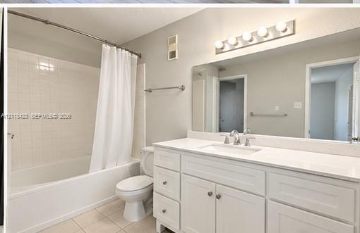 Bathroom featuring a white vanity with an integrated countertop, large wall-mounted mirror, five-bulb vanity light, and a white tile tub surround