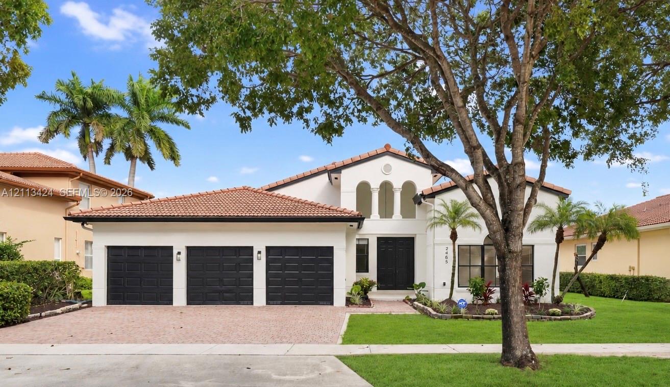 Stucco exterior featuring a clay tile roof, three-car garage, arched architectural detailing, and landscaped grounds