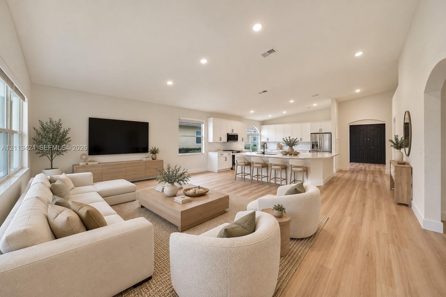 virtually staged Open-concept interior featuring vaulted ceilings, wood-finish flooring, recessed lighting, and a kitchen island with stone countertops