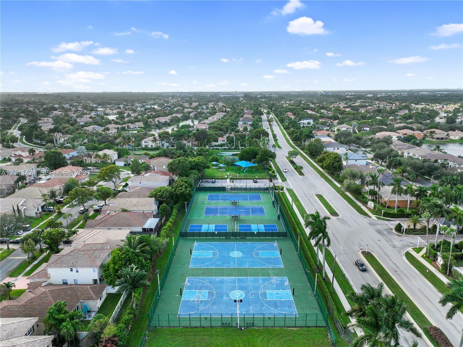 Aerial perspective of recreational facilities including two fenced tennis courts and two basketball courts with integrated lighting